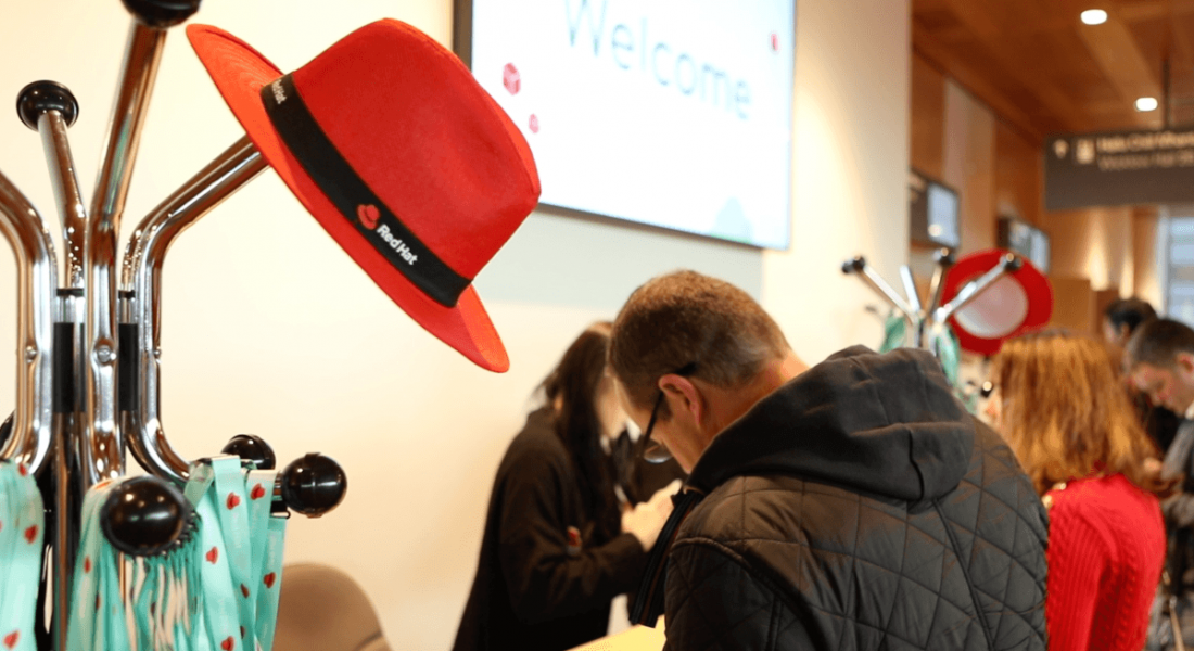 A red hat sitting on a hat stand at a conference.