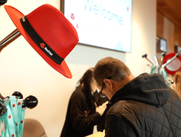 A red hat sitting on a hat stand at a conference.