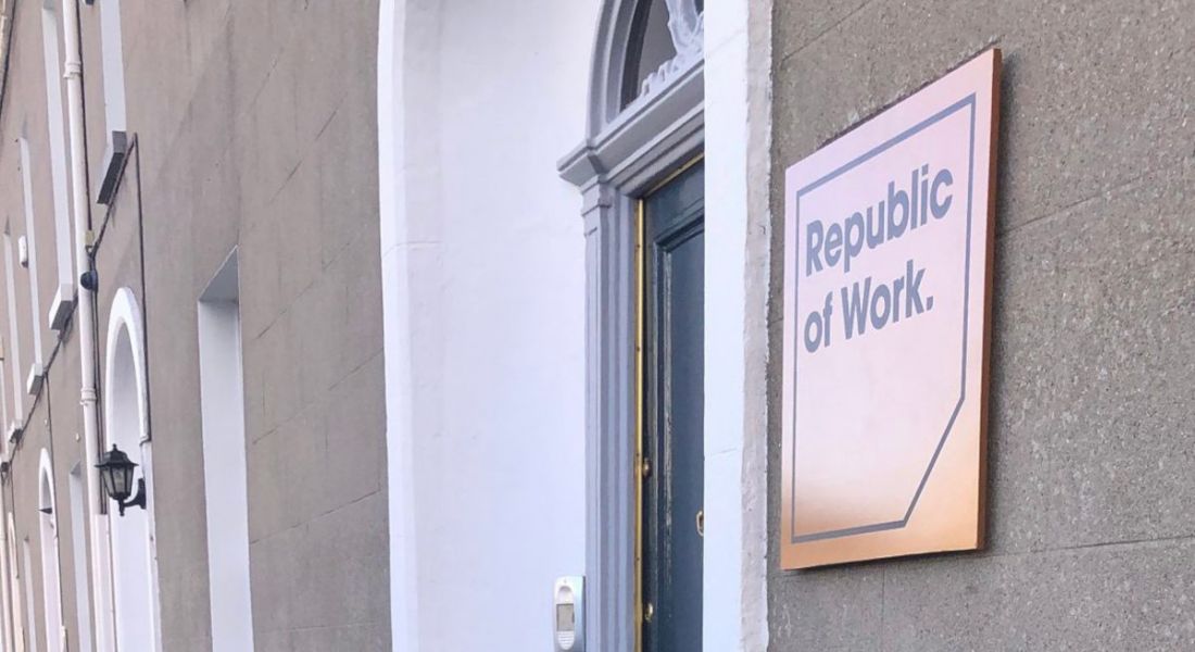 The door of Republic of Work with a plaque on the wall beside it.