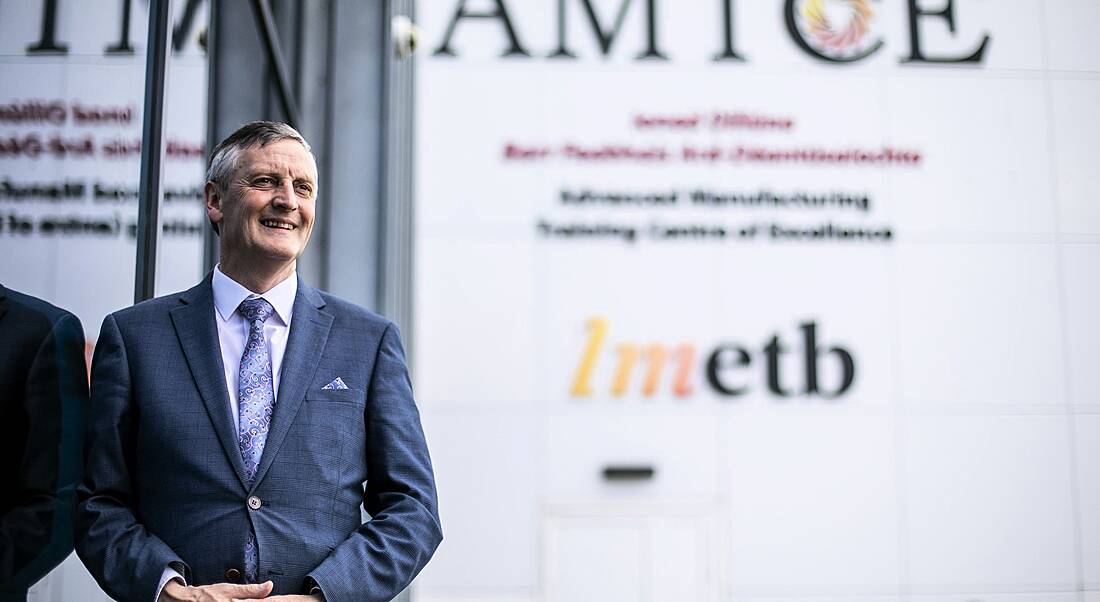 Martin O'Brien standing against a grey wall with the AMTCE and LMETB branding on it.