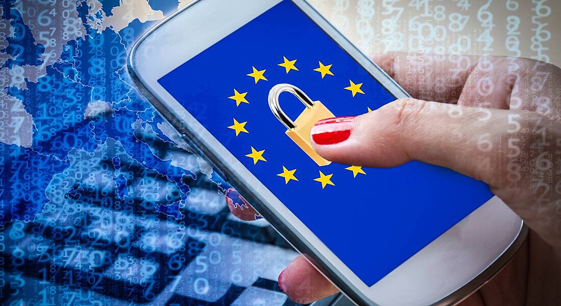 Person's hand holding a phone with a lock and an EU flag on it in a cybersecurity concept.