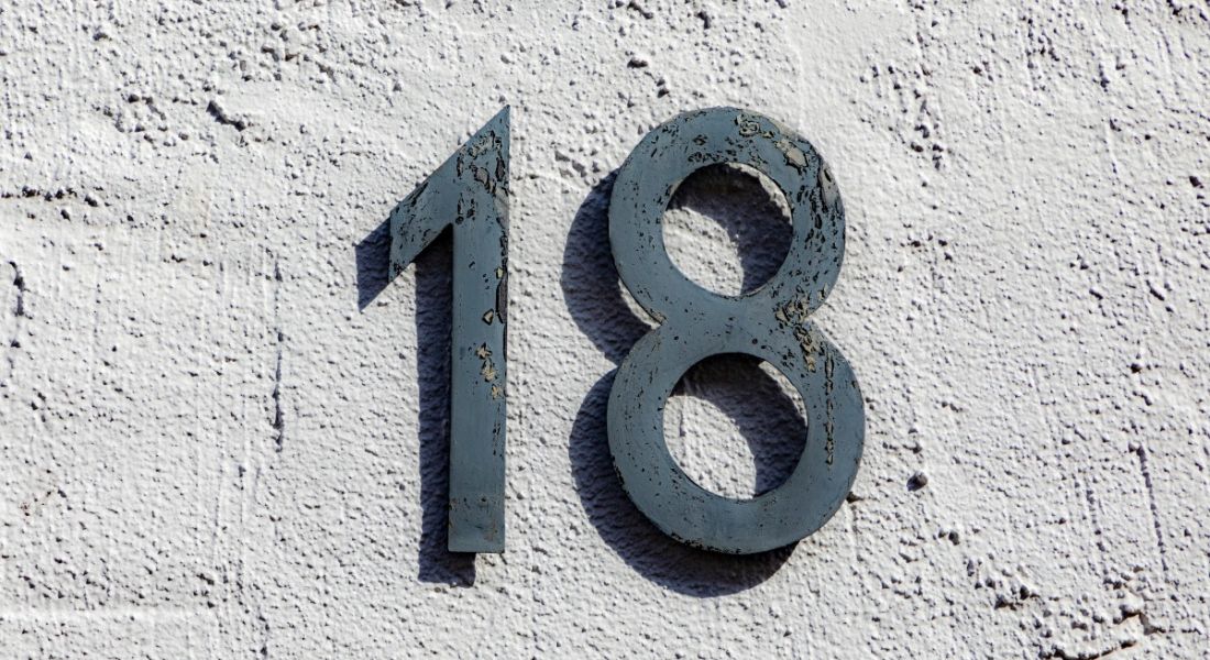 the number 18 in grey lettering on a light grey wall.