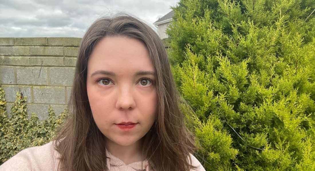 A woman smiles at the camera with a tree behind her. She is Agata Dzierzak, a software engineer at Fidelity Investments.