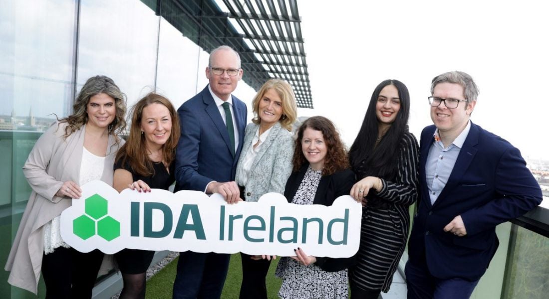 Men and women stand next to each other holding a cut-out that reads IDA Ireland.