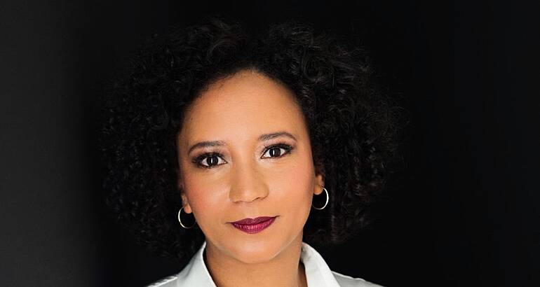 A woman smiles at the camera with a dark background behind her. She is Tamarisk Scholtz, a governance risk and compliance security manager at Accenture.