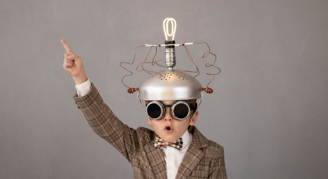 Child wearing a mad scientist costume and pointing in the air in a creativity concept.
