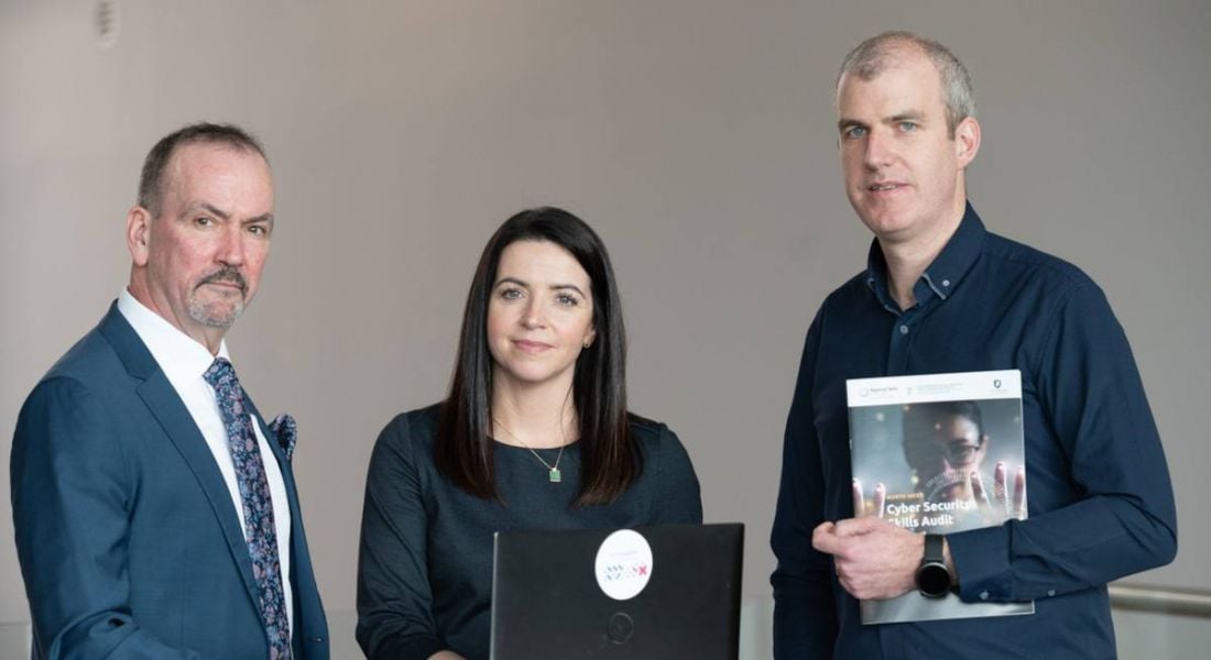 Three people standing together holding the cybersecurity skills report for the North West in Ireland.