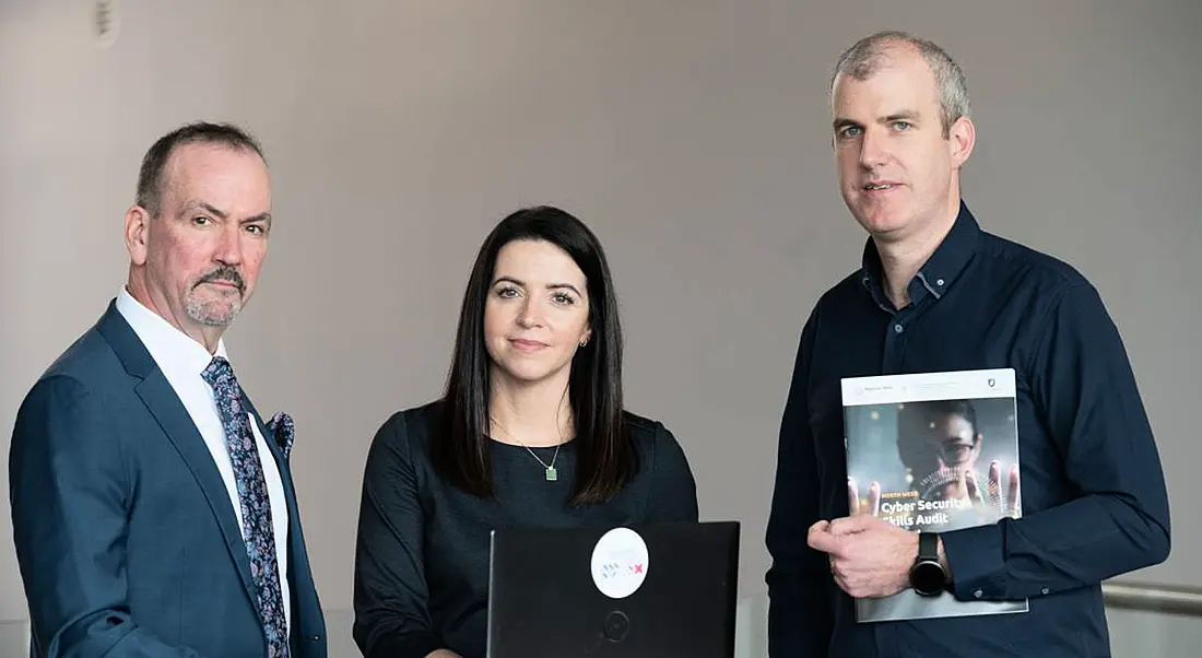 Three people standing together holding the cybersecurity skills report for the North West in Ireland.