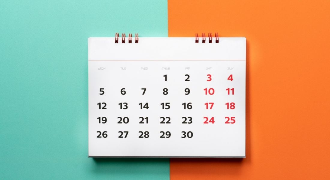 A small spiral calendar lies flat on an orange and blue background, representing notice periods at work.
