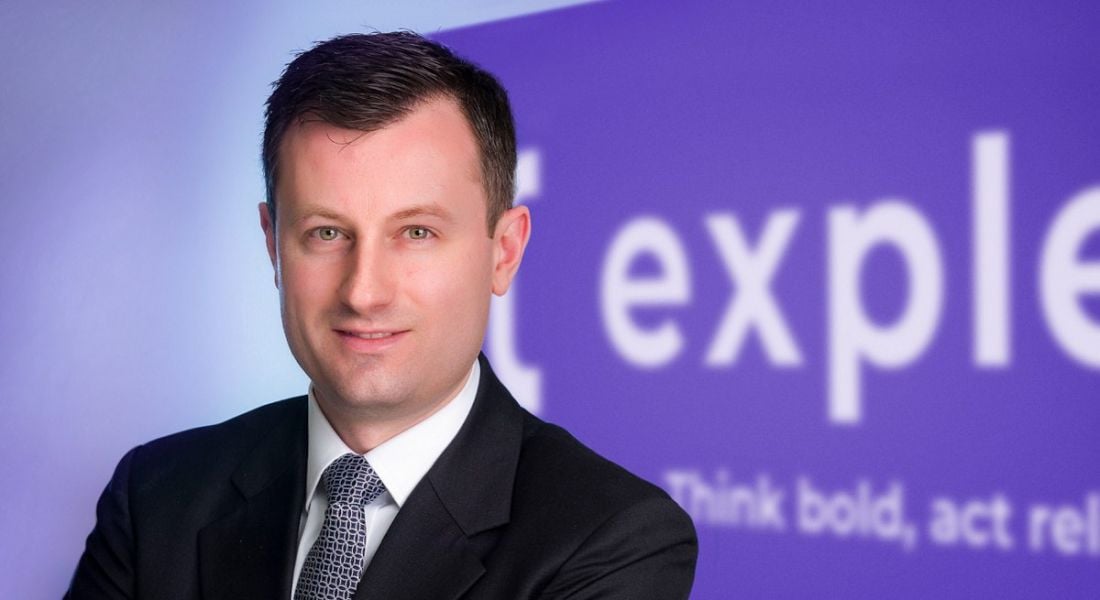 Paul O'Malley, COO of Expleo Ireland standing in front of a purple sign with the Expleo logo partially visible in white writing.