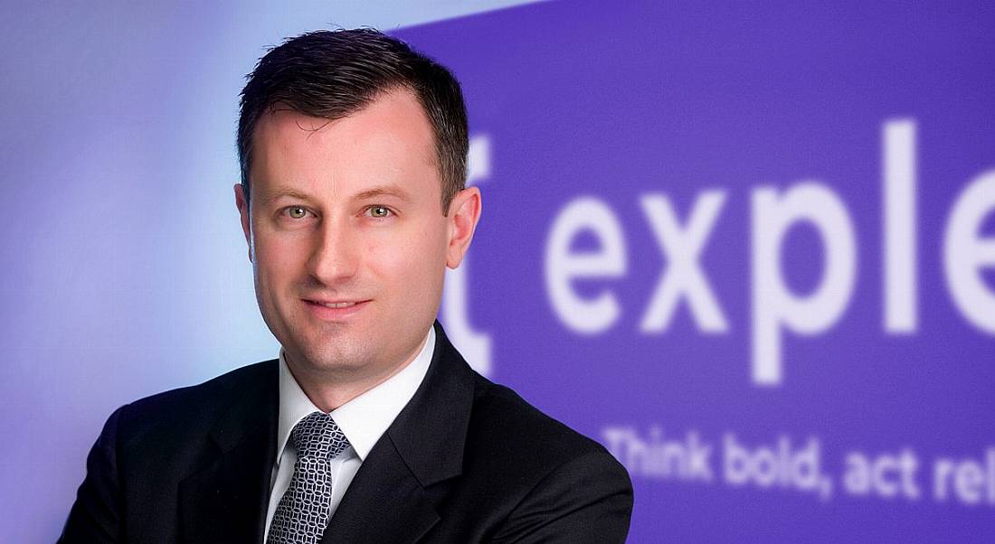 Paul O'Malley, COO of Expleo Ireland standing in front of a purple sign with the Expleo logo partially visible in white writing.