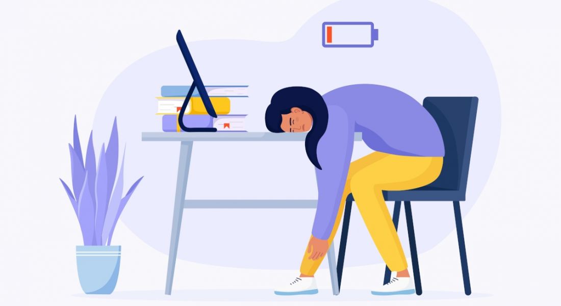 An illustration of a woman slumped at her work desk with a low battery symbol floating above her, symbolising burnout.