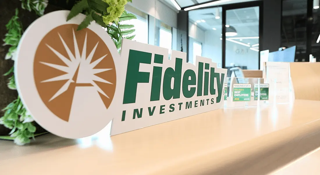 A sign depicting the logo of Fidelity Investments sits on a desk in an office setting.