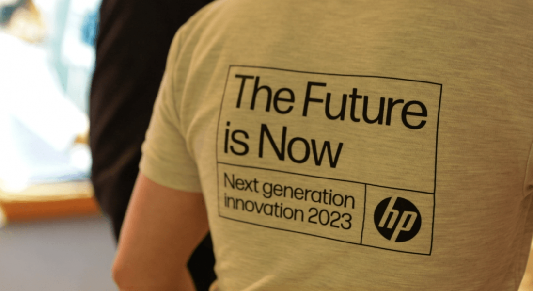 A close-up of the back of a man's grey t-shirt with the words 'The future is now. Next generation innovation 2023' and the HP logo on it.