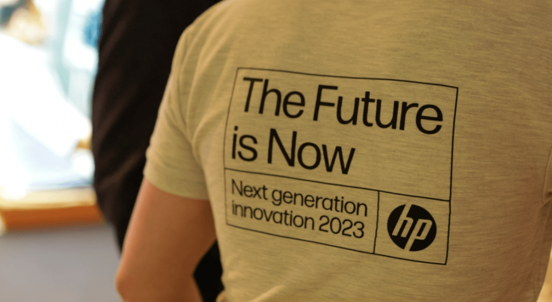 A close-up of the back of a man's grey t-shirt with the words 'The future is now. Next generation innovation 2023' and the HP logo on it.