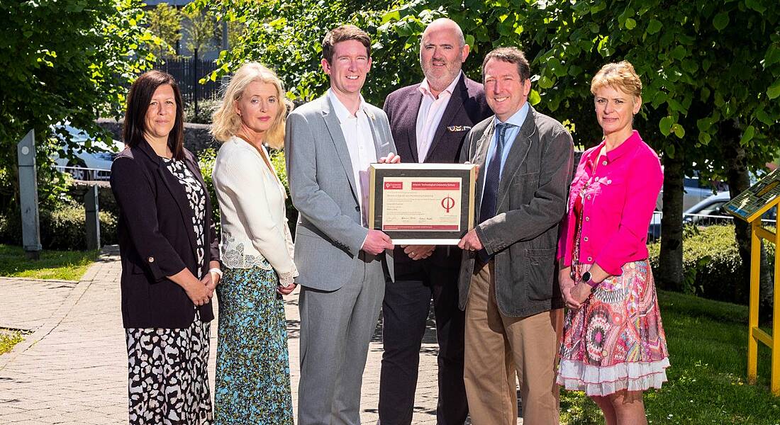 Six people standing outside ATU Galway campus with trees behind them. They are holding a certificate of accreditation from Engineers Ireland.