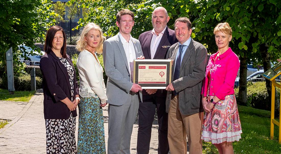 Six people standing outside ATU Galway campus with trees behind them. They are holding a certificate of accreditation from Engineers Ireland.