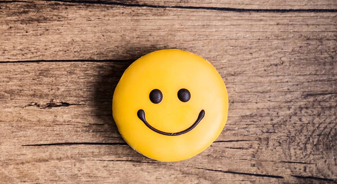 A smiley face on a wooden surface, symbolising staying positive between freelancing jobs.