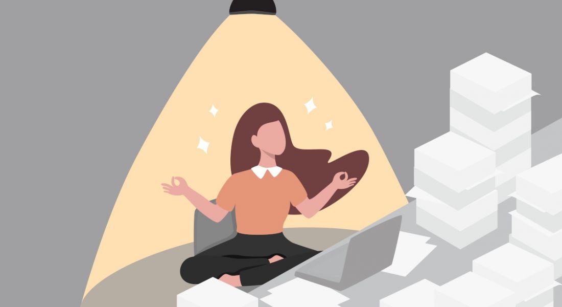 Cartoon of a worker building resilience skills. She is sitting in the lotus position by her desk which is covered in piles of paper and a laptop. There is a light shining on her from above.