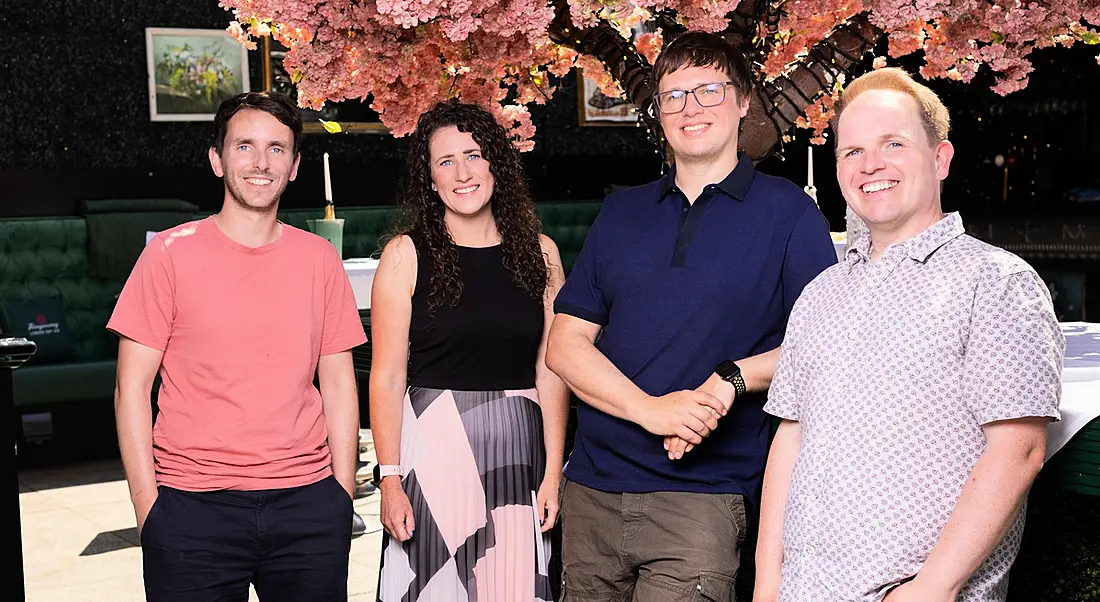 Three men and a women who work at SciLeads standing in a row in front of a cherry blossom tree in full bloom.