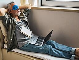 Image of a man surrounded by folders and stacks of paper. An email notification symbol showing 100 emails floats beside him. He looks stressed.