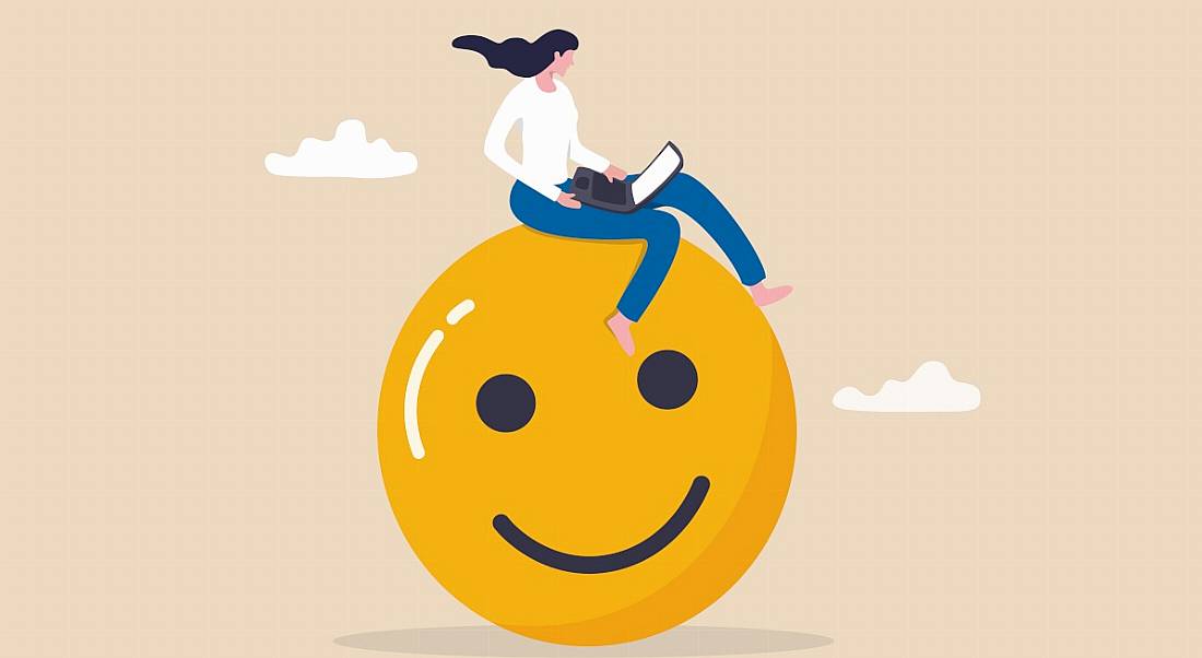 An illustration of a woman sitting on top of a giant smiley face while using her laptop.