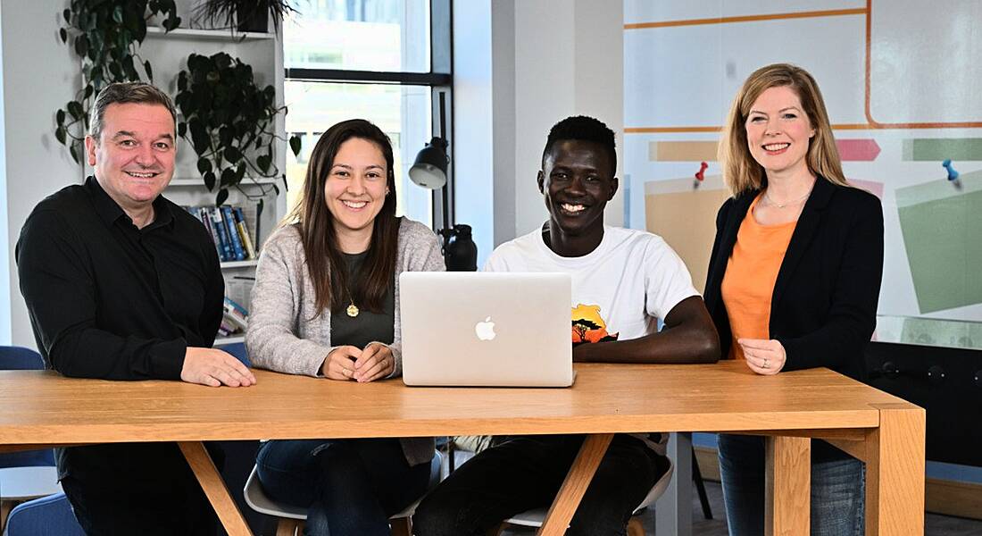 Four people from Liberty IT sitting at a desk with a laptop in an office.