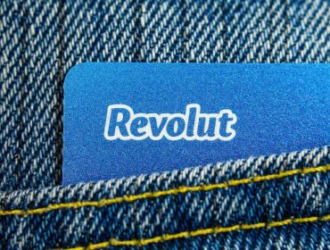 A close-up of a pocket on a pair of blue jeans with a blue Revolut card sticking out.