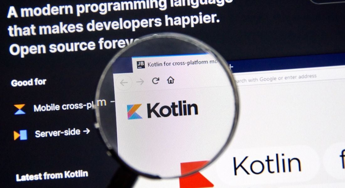 A magnifying glass hovering over the Kotlin logo on a search engine displayed on a screen.