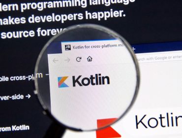 A magnifying glass hovering over the Kotlin logo on a search engine displayed on a screen.