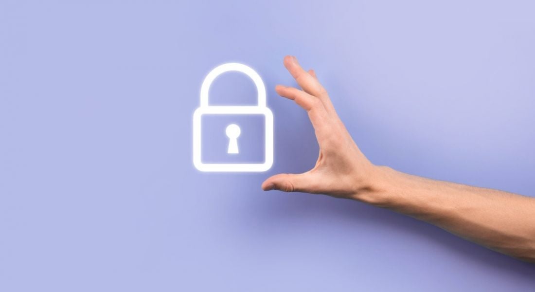 Person's hand reaching out towards a white lock icon that is on a light purple background to symbolise a privacy concept.