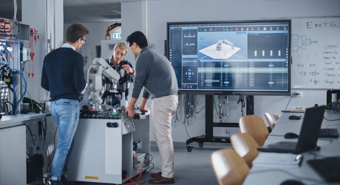 Students in a computer lab with a robot hand in a machine learning and AI concept.