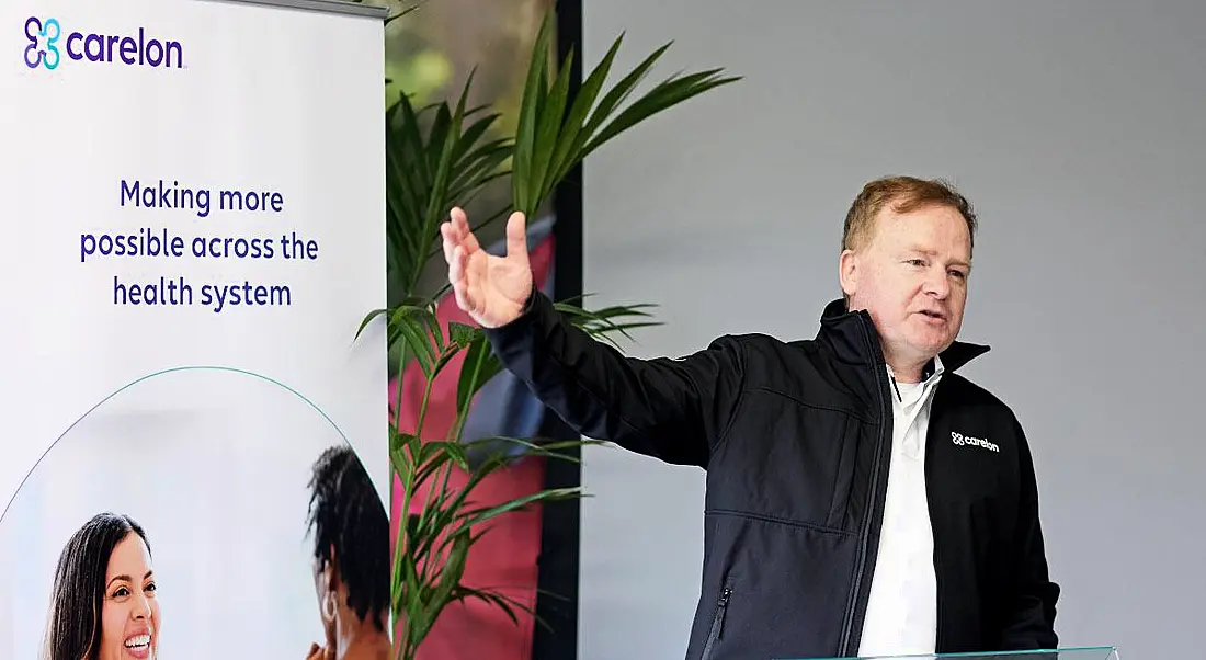 Carelon Global Solutions Ireland country head John Patrick Shaw speaking on a podium with the company branding behind him.