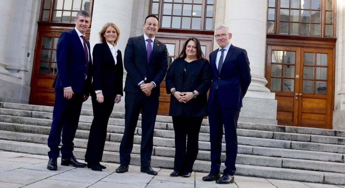 Five people from the Irish Government and Siemens Healthineers standing outside a building with steps in front of it.
