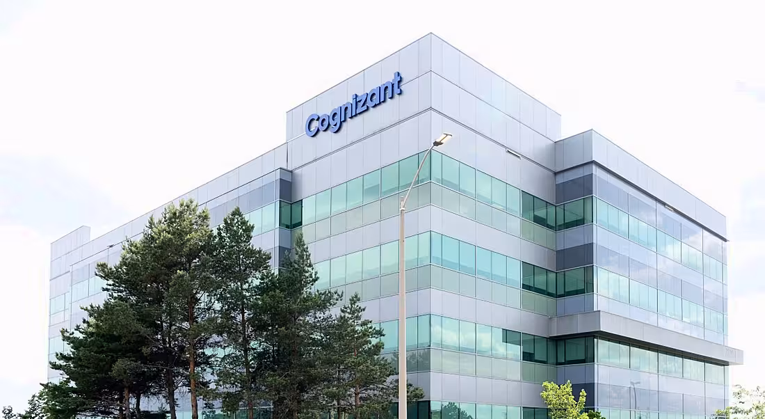 A tall building with the Cognizant logo on top, with a grey sky in the background.