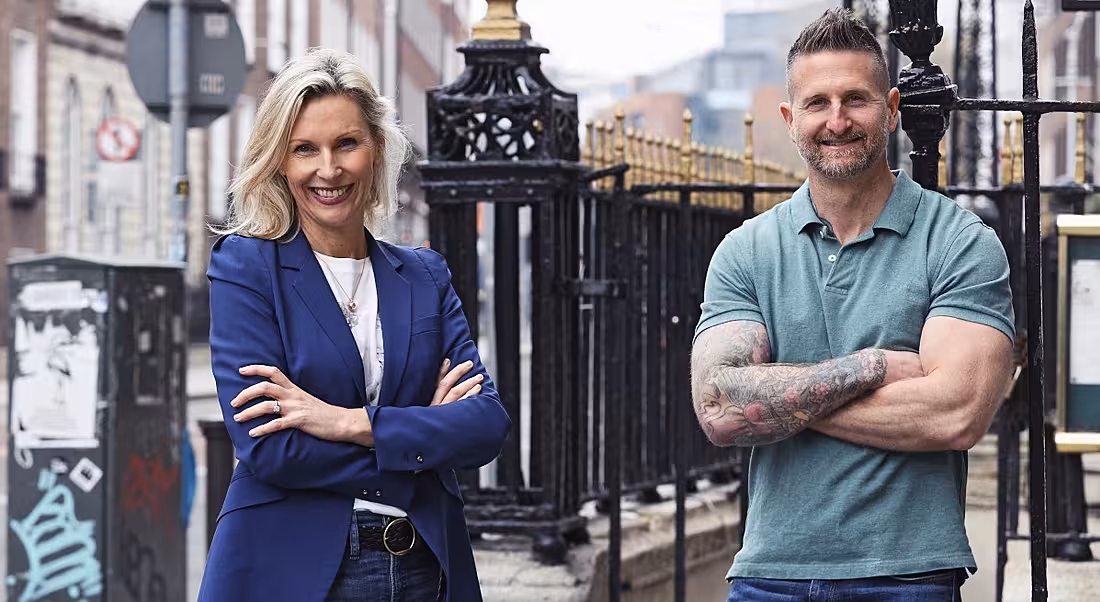 A man and a woman who work at Lucky Beard standing outside leaning against some railings.