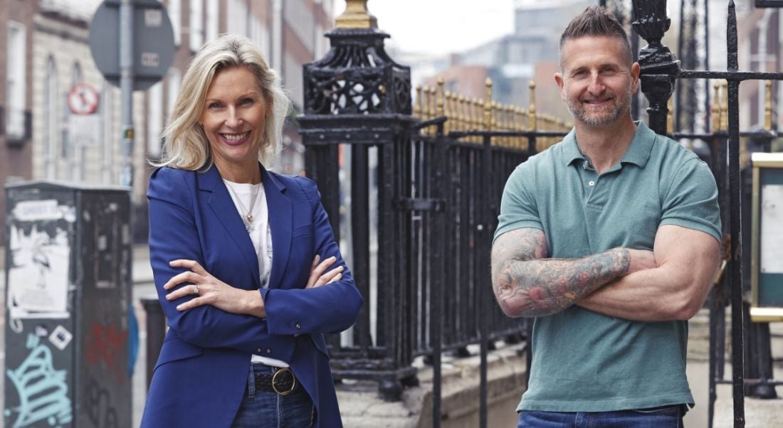 A man and a woman who work at Lucky Beard standing outside leaning against some railings.