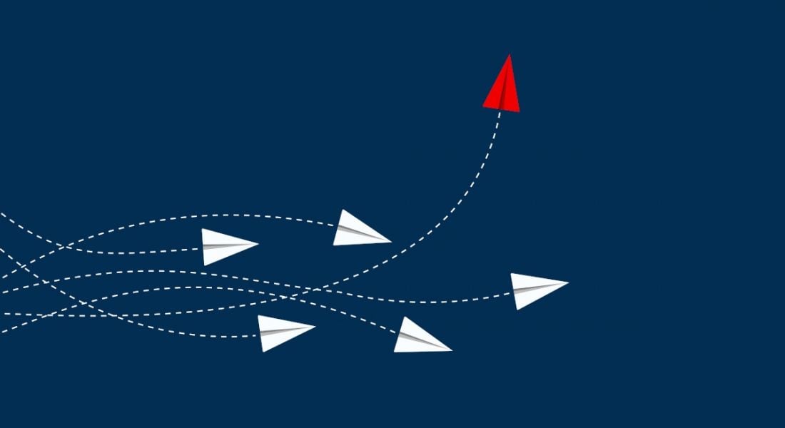 A group of white paper aeroplanes weaving in different direction. One red one is veering upwards, symbolising changing jobs.
