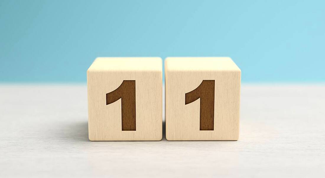 Two wooden blocks side by side displaying the number 11 against a blue background.