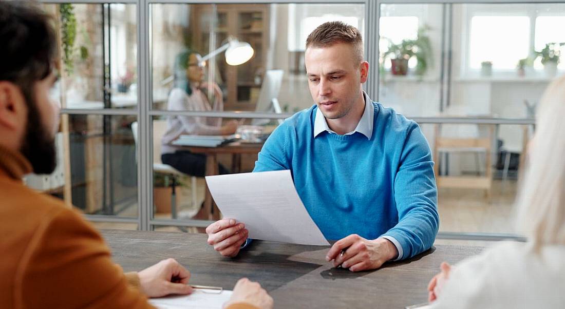 A man holding a CV while sitting in front of two other people. He is applying for a data science job.