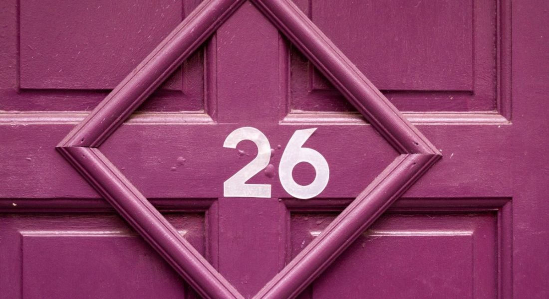 The number 26 on a pink painted door.