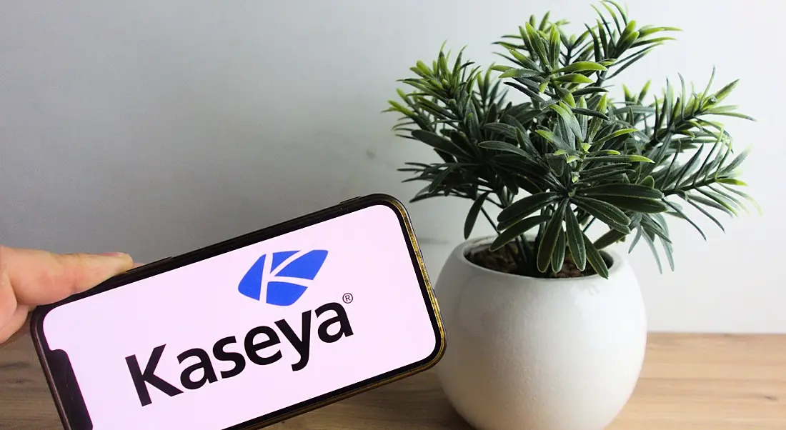 A phone with Kaseya branding on the screen with a potted plant beside it.