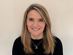 A woman smiles in front of a light coloured wall. She is Jess Wyer, a cyber risk analyst at Deloitte.
