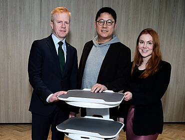 Three people with a robot built by Bear Robotics.