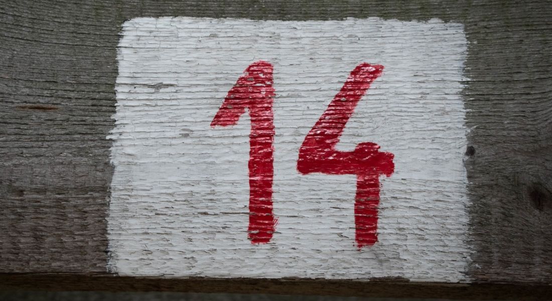 A red number 14 painted on a wooden plank.
