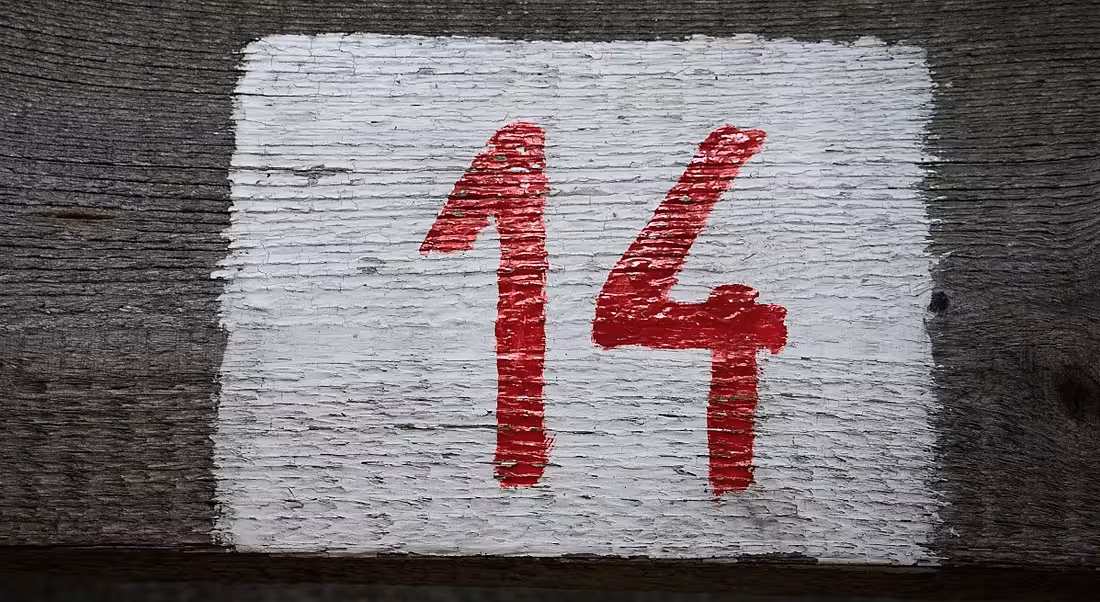 A red number 14 painted on a wooden plank.