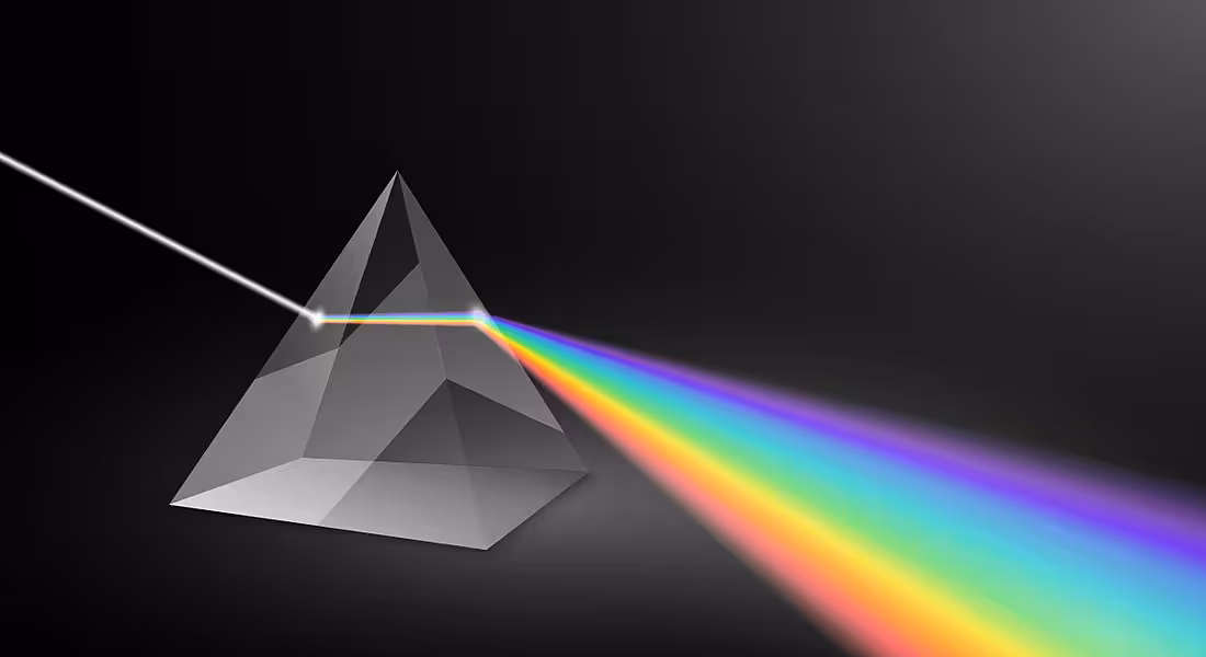 A prism expands light into beams of rainbow colour against a dark background.