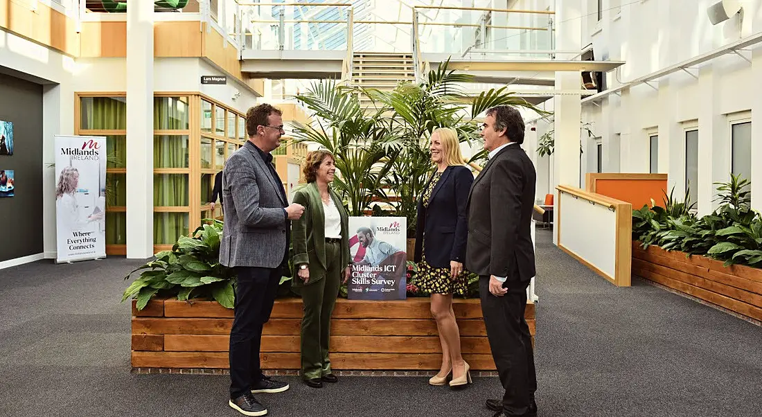 Four people involved in the midlands regional skills forum report standing around a copy of the report. They are all in the lobby of a large, airy building.