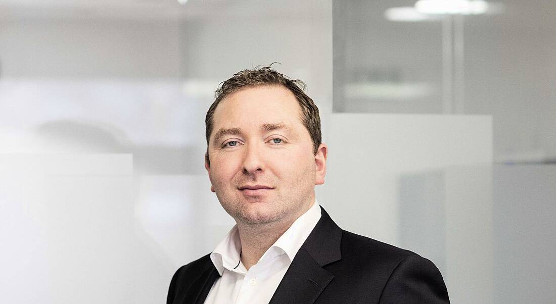 A man in a suit standing in a white room. He is Philip Smith, the managing director of Leo Lynch.