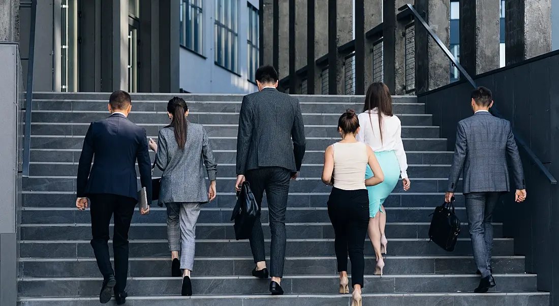 Employees making the return-to-office journey walking up a set of steps to a building.